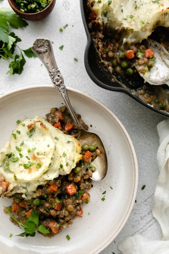Lentil shepherd's pie plated on a cream plate topped with baked mashed potatoes.