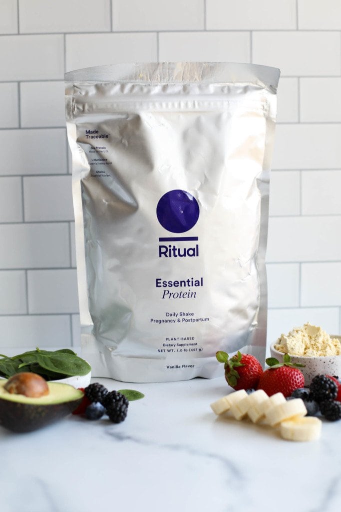 A bag of Ritual Plant Based protein powder against a white background with fresh cut berries in the forefront. 