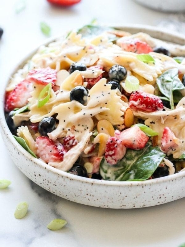 Close up view of summer pasta salad with bow tie noodles, chicken, and berries.
