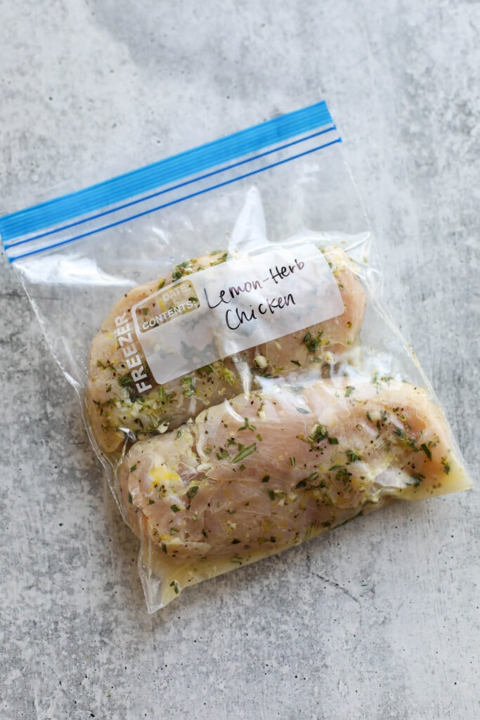 Overhead view of chicken breasts in a ziplock bag with lemon herb chicken marinade.