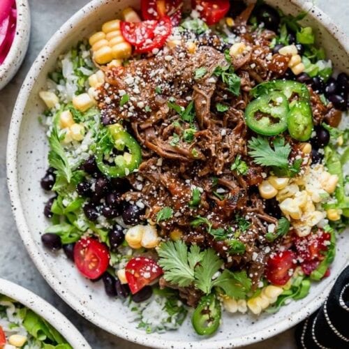 Overhead view of instant pot beef barbacoa served as a burrito bowl for a round up of easy dinner recipes.
