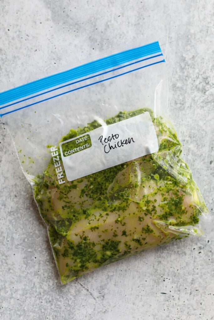 Overhead view of basil pesto chicken marinade with two chicken breasts in a ziplock bag. 