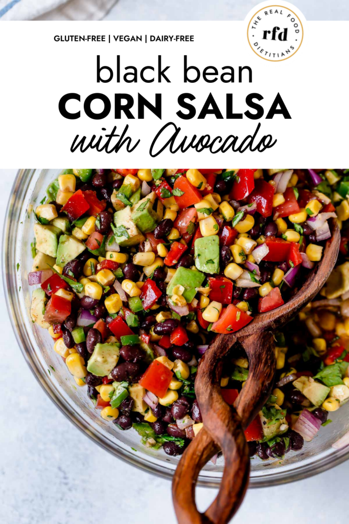 Overhead view of black bean and corn salsa with avocado mixed together with chili lime vinaigrette in a clear glass mixing bowl. 