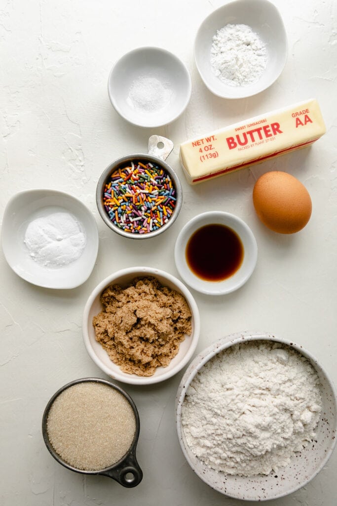 All ingredients for gluten free funfetti cookies arranges together in small bowls and measuring cups. 
