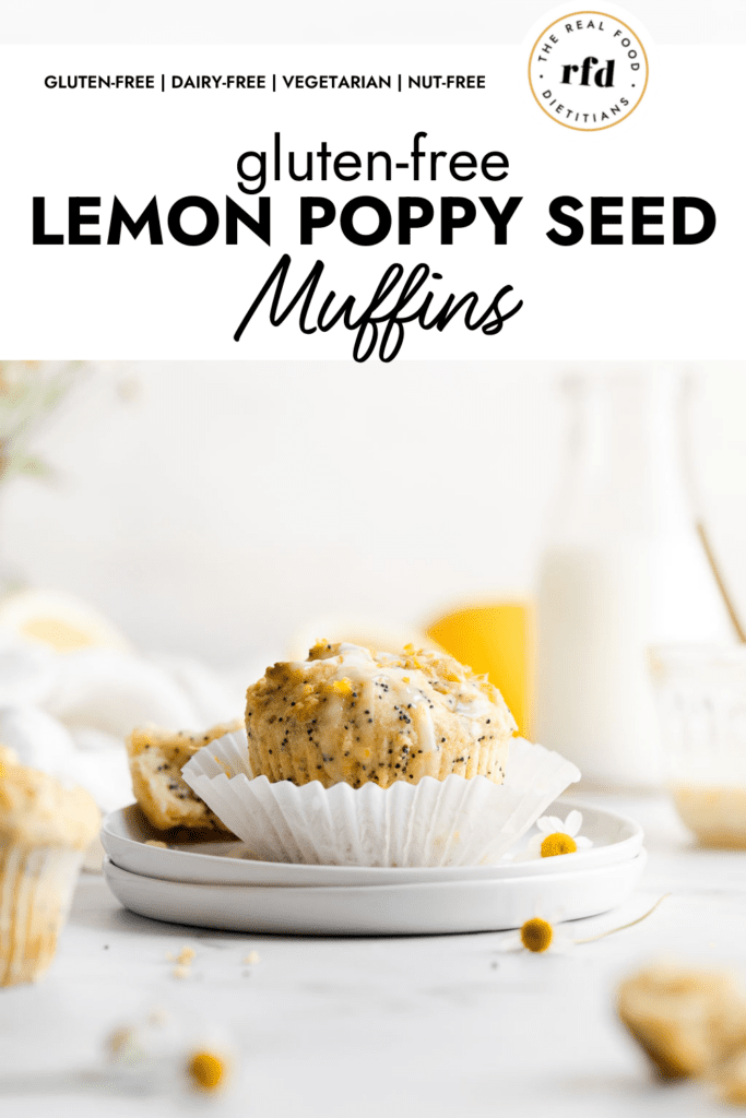 A single lemon poppy seed muffin topped with lemon glaze and lemon zest sitting on a fanned out white muffin liner placed on two stacked up small plates. 