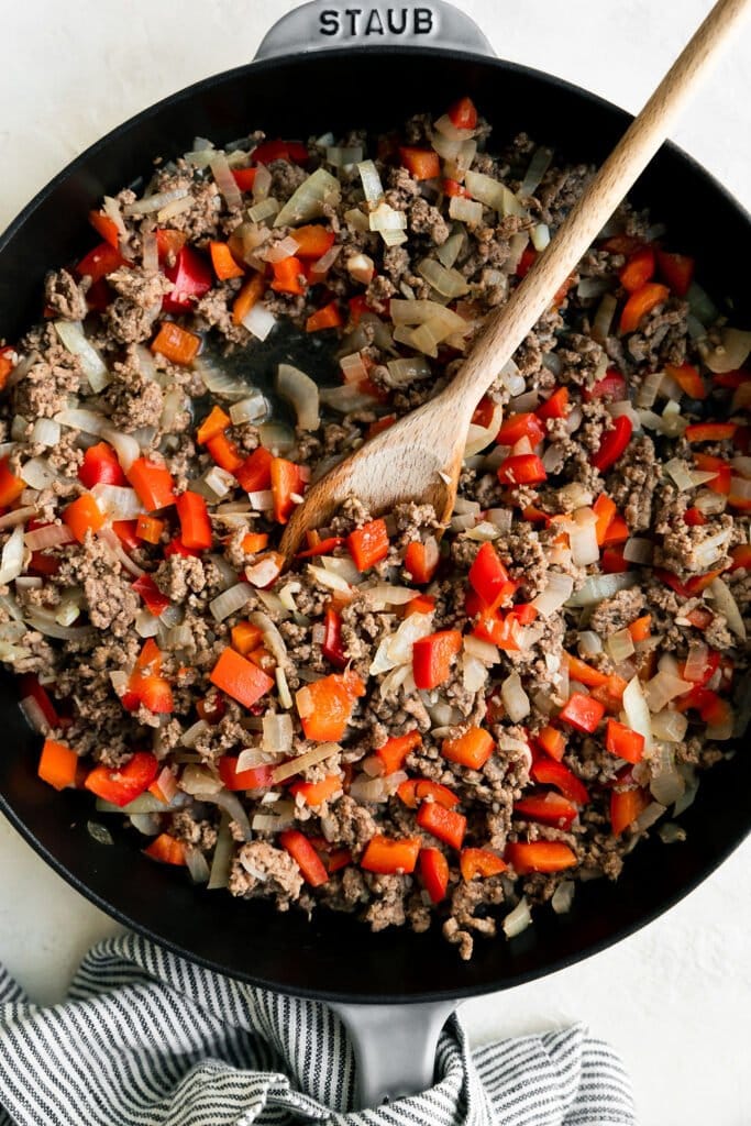 Overhead view of browned ground beef, peppers, and onions in a skillet