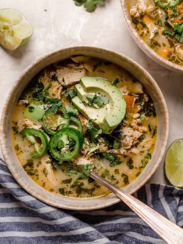 A bowl of Slow Cooker White Chicken Chili topped with sliced jalapenos and avocados. 
