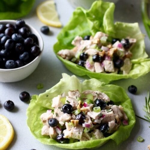 Two butter lettuce wraps filled with blueberry chicken salad with rosemary.