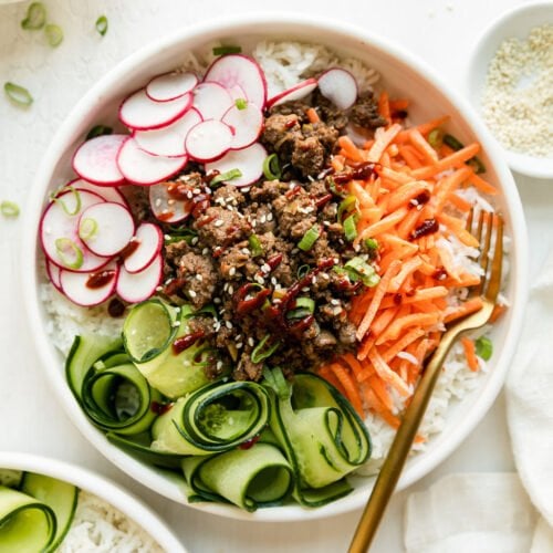 Overhead view of Korean-inspired Ground Beef Bowl served over rice in white bowl.