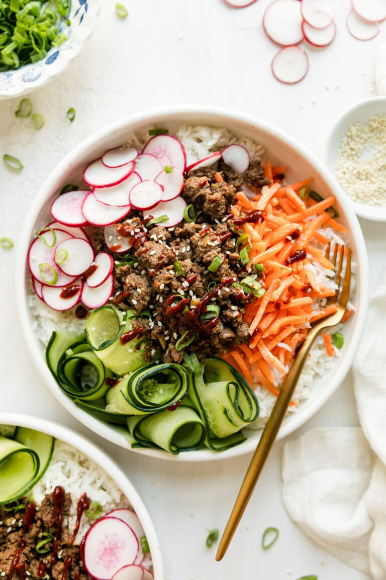 Overhead view of a Korean-Inspired Ground Beef Bowl with sliced radishes, shredded carrots, and cucumbers. 