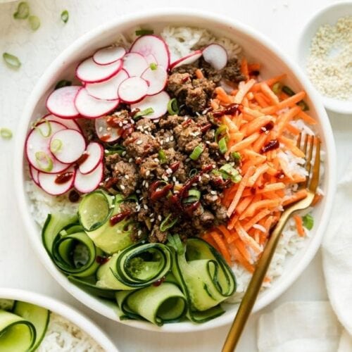 Overhead view korean-inspired ground beef bowl served over rice in white bowl.