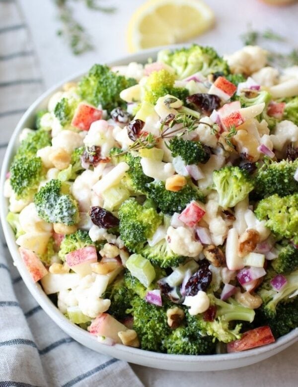 Apple broccoli cauliflower salad in a white serving bowl.