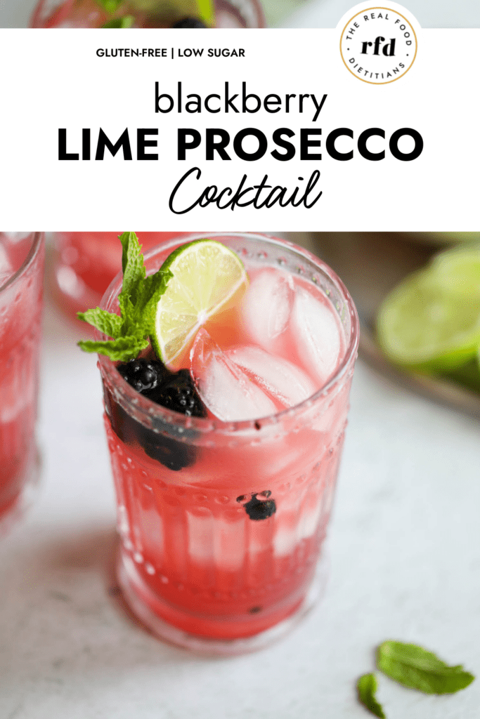 Blackberry lime prosecco cocktail in tall glass with fresh mint, lime slice, and fresh blackberries as garnish.