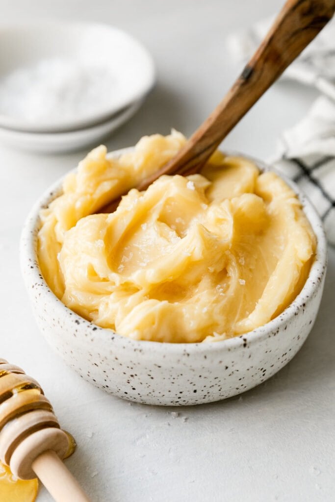 Whipped honey butter in small bowl with wooden spoon in butter. 