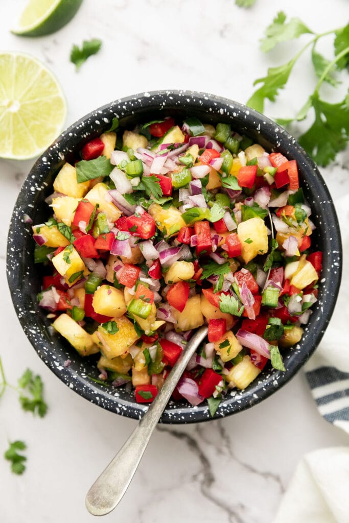 Overhead view black speckled bowl filled with pineapple salsa.