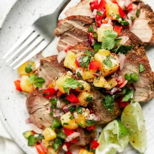 Overhead view grilled pork tenderloin with pineapple salsa served on plate.