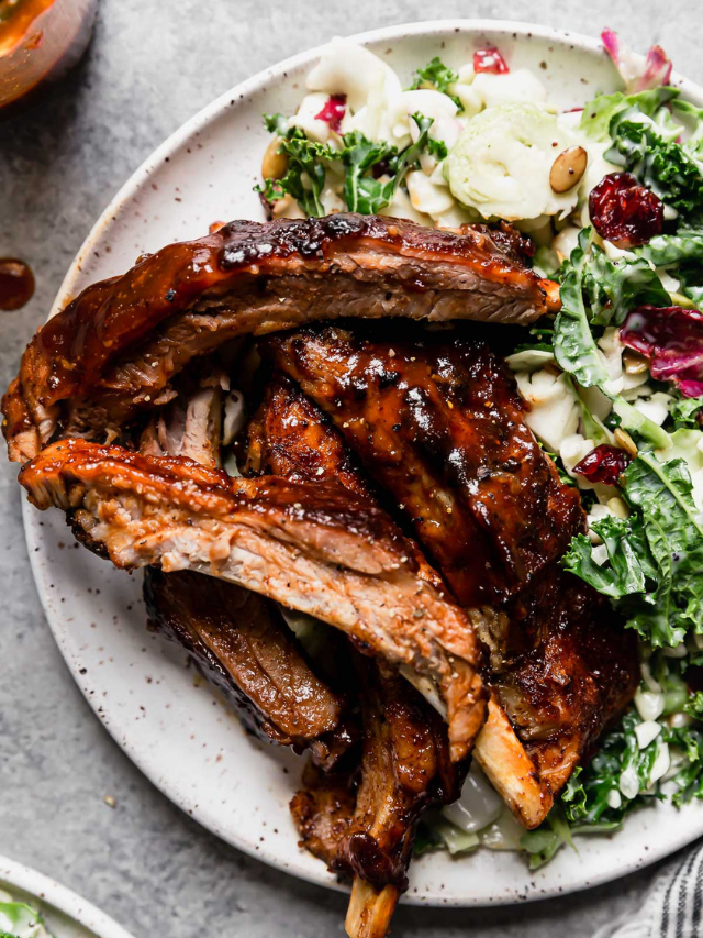 Instant pot baby back ribs with bbq sauce plated on white plate with sweet kale salad on side.