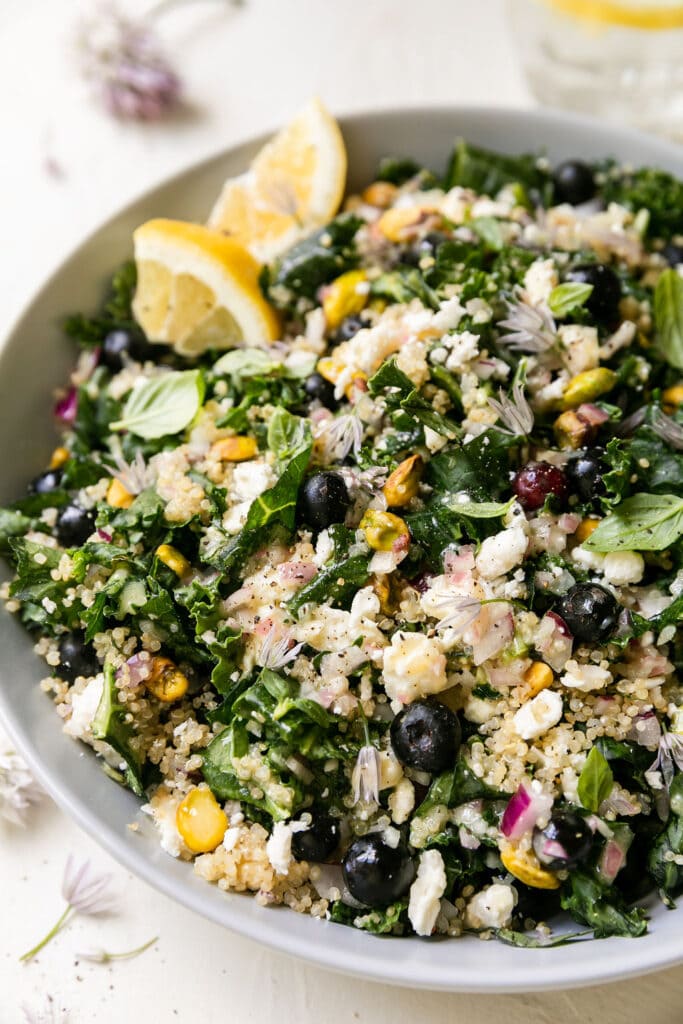 Close up view quinoa kale salad with blueberries, pistachios, and feta cheese crumbles. 