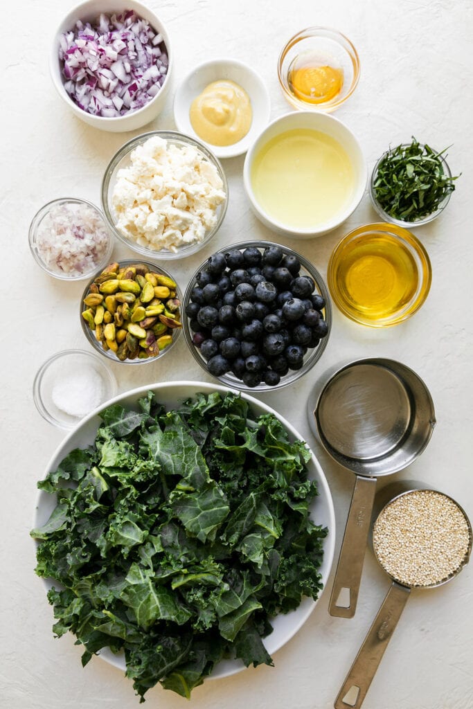 All ingredients for quinoa kale salad with blueberries and feta in small bowls.