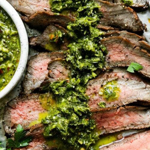 Grilled flank steak cut into thin strips with herb sauce over top.