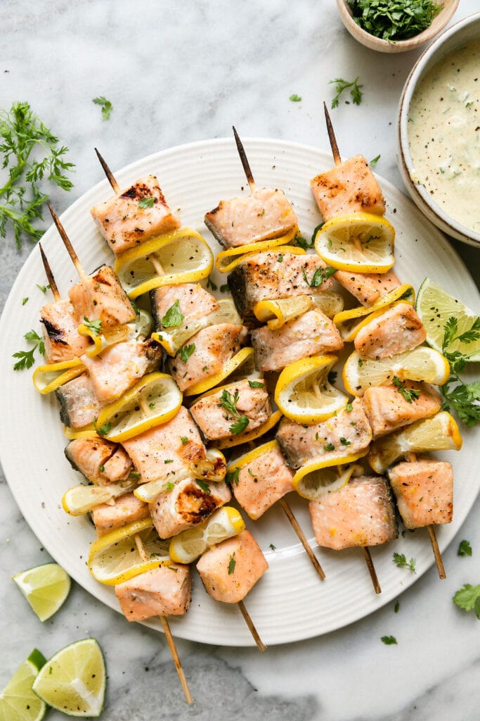 Overhead view plateful of grilled salmon kabobs with lemon.