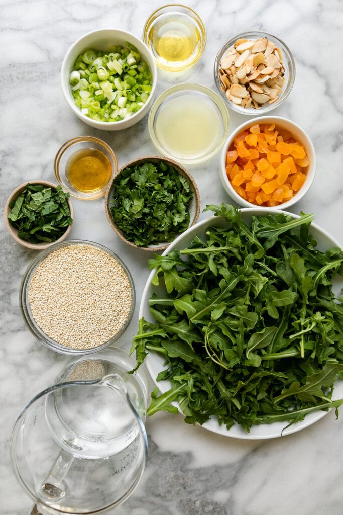 All ingredients for herbed quinoa pilaf in small bowls arranged together. 