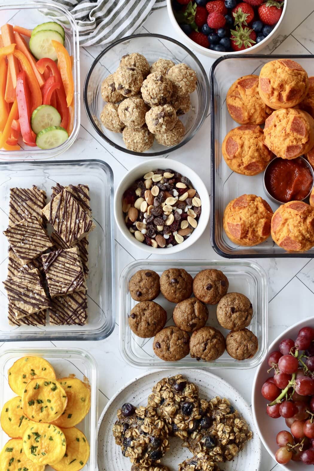 Overhead view of a variety of sweet and savory snacks in different containers. 