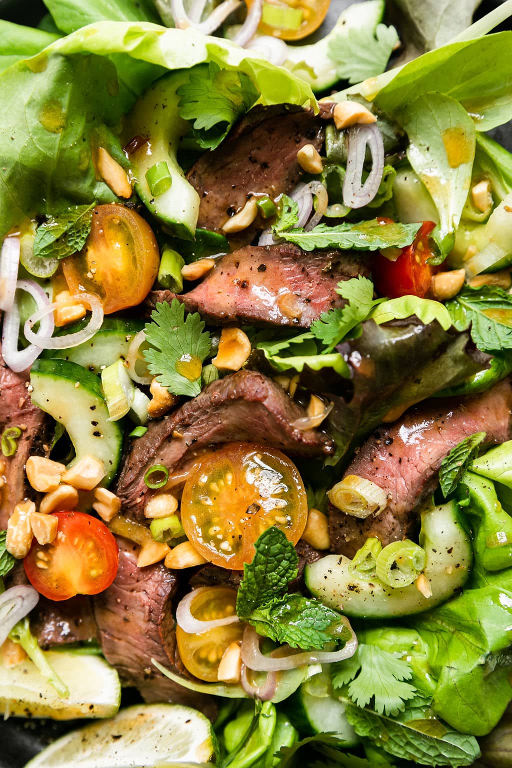 Close up view steak salad with Thai dressing drizzled over top. 