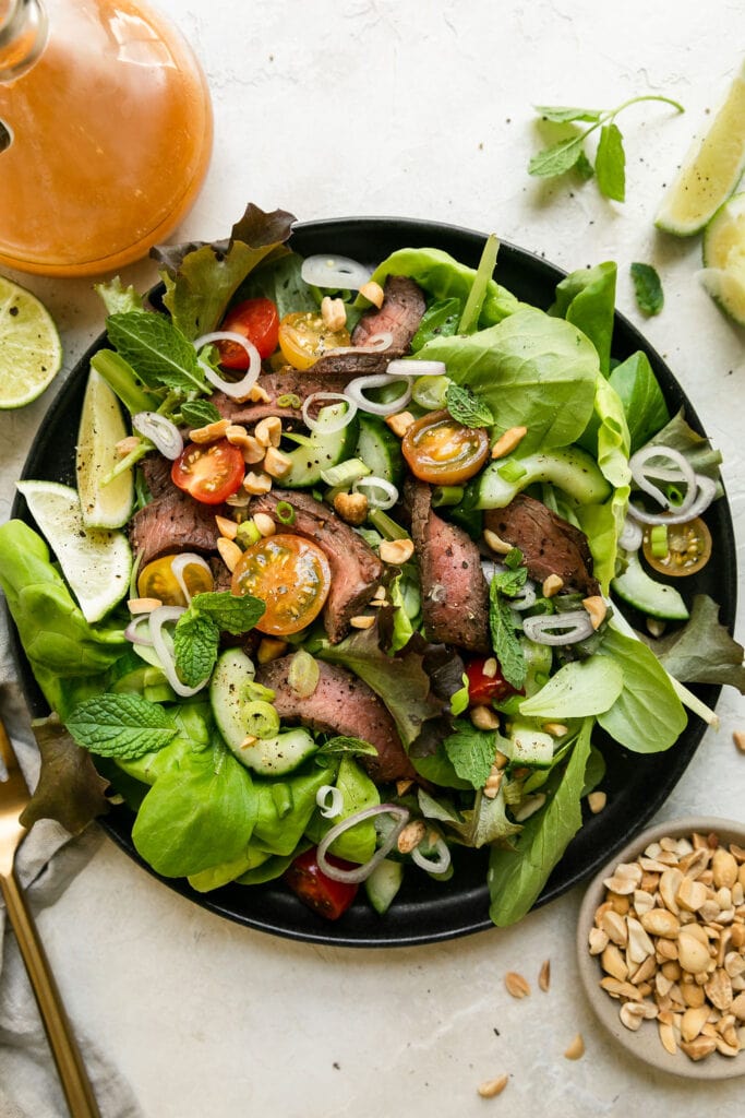Overhead view Thai-inspired Steak Salad on a black plate. 