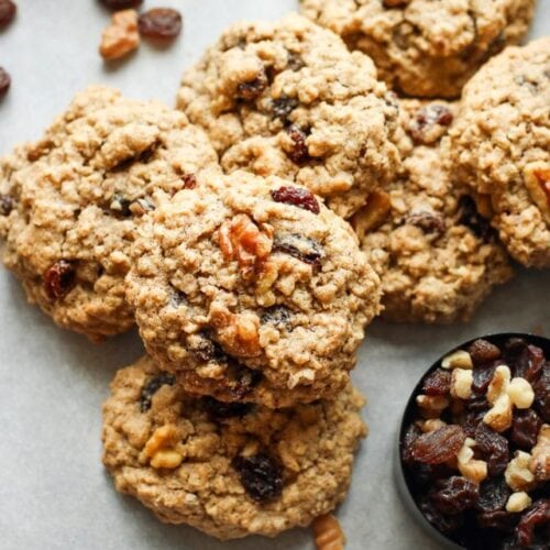 A pile of oatmeal raisin cookies topped with walnuts