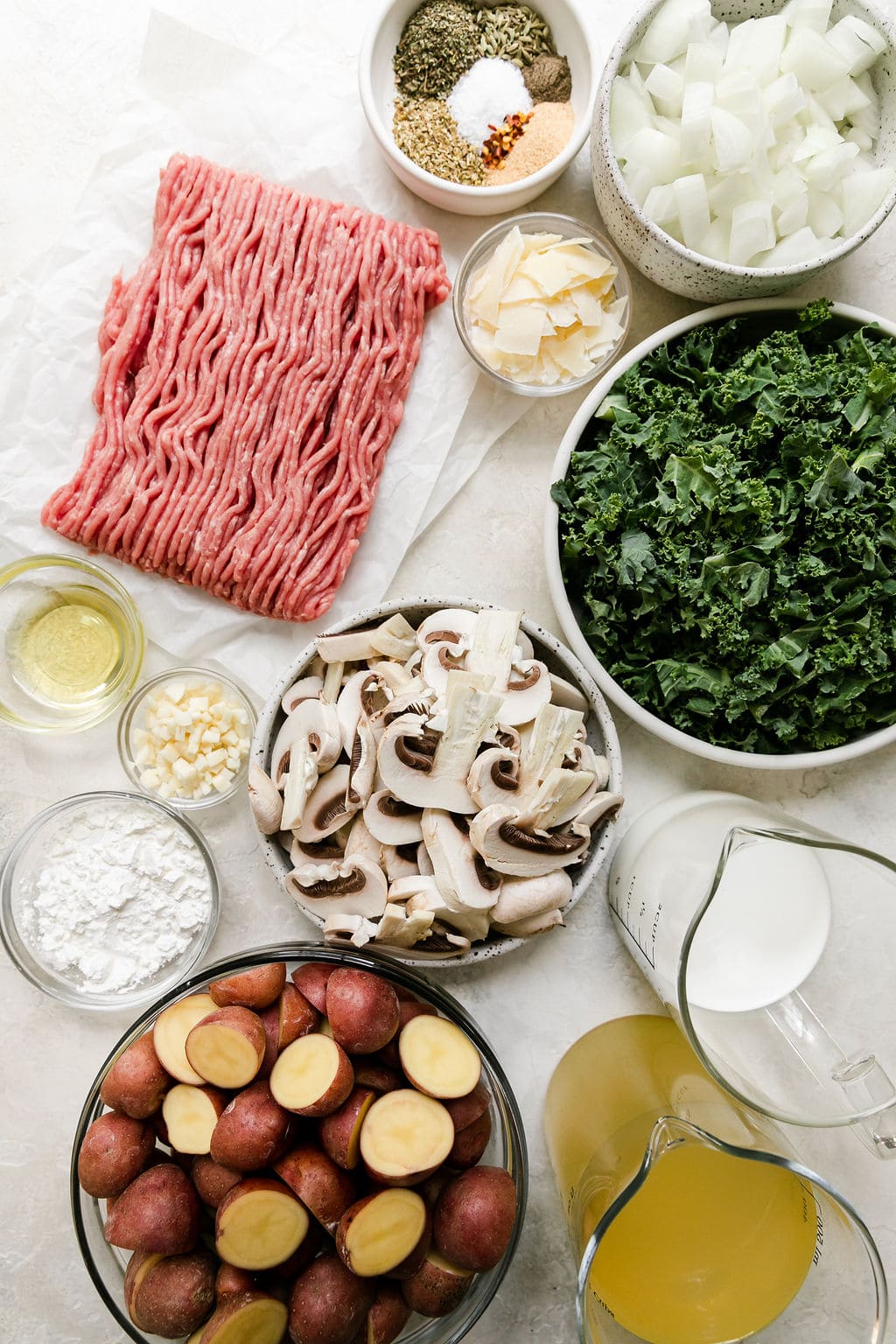 All ingredients for copycat Olive Garden Zuppa Toscana arranged in bowls and on parchment paper.