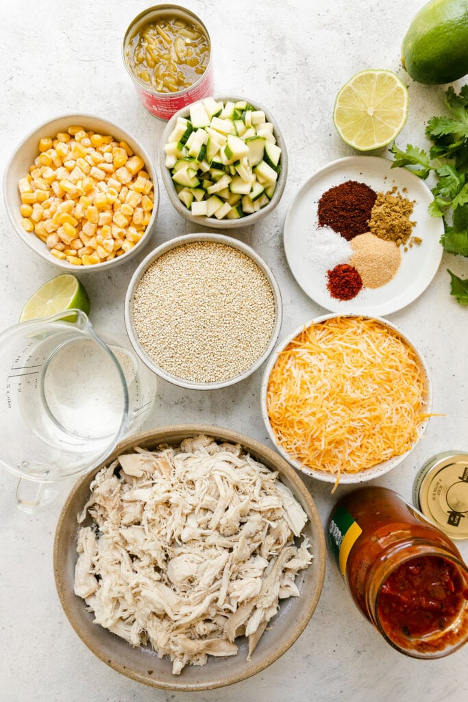 All ingredients for chipotle quinoa chicken casserole arranged in small bowls, cans, and measuring cups 