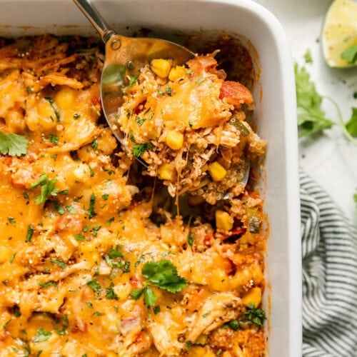 A white baking dish filled with chipotle quinoa casserole with chicken, a spoon full of
