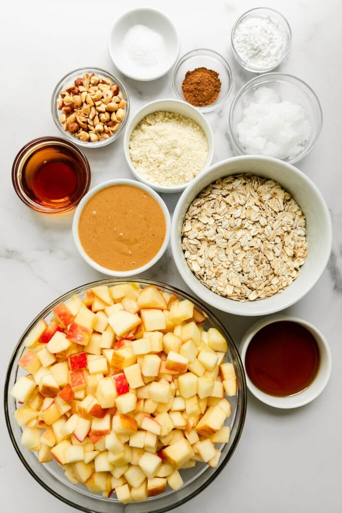 All ingredients for peanut butter apple crumble arranged in small bowls.