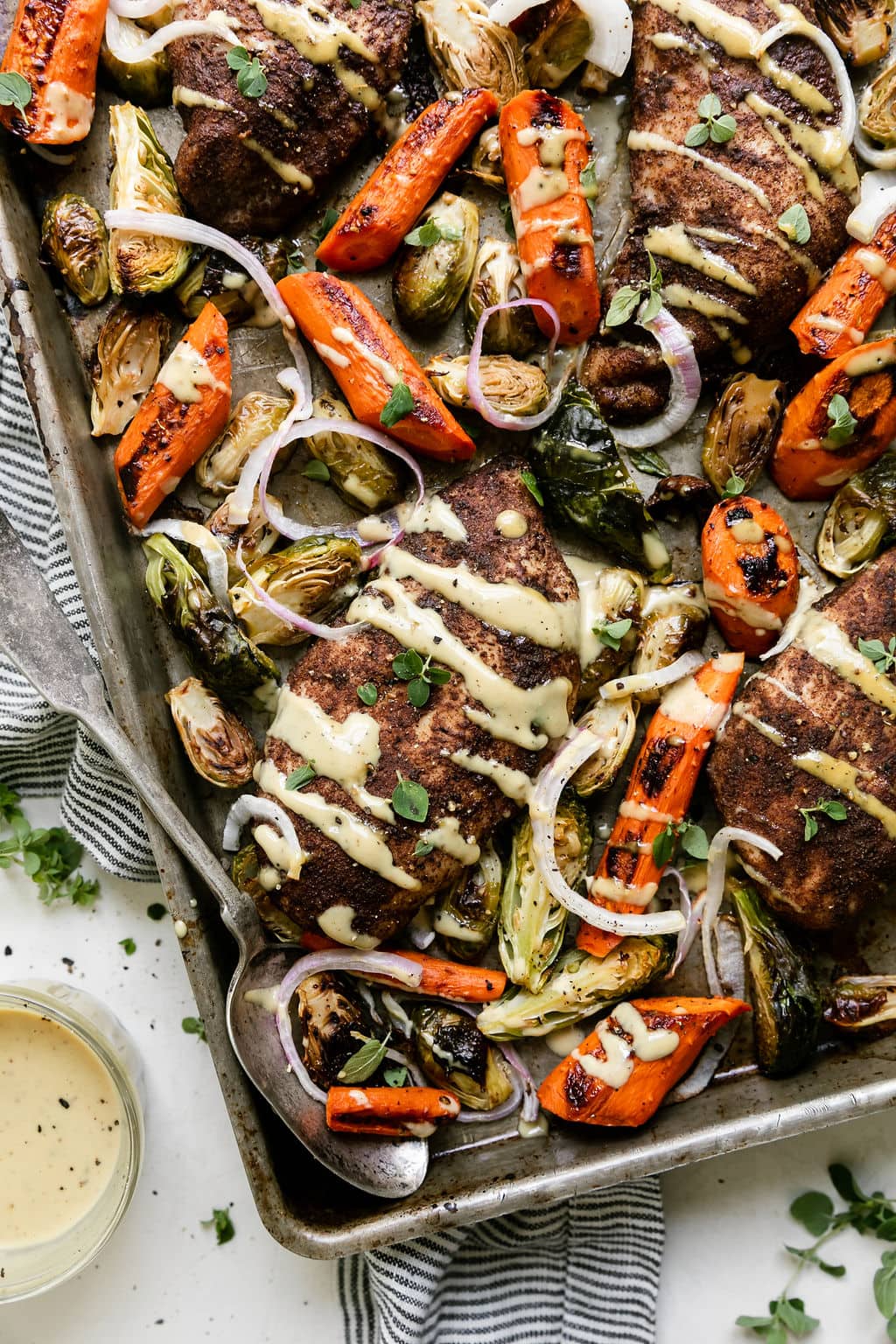 Sheet pan Harvest chicken with roasted veggies, maple dijon dressing drizzled over top.