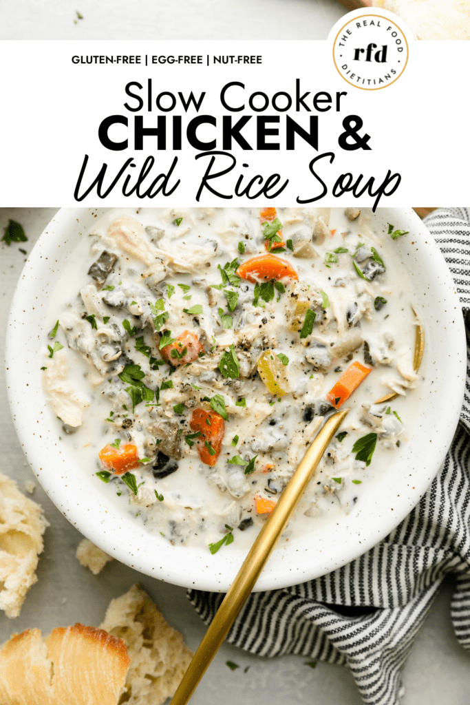 Overhead view creamy chicken wild rice soup in a bowl topped with fresh herbs and black pepper.