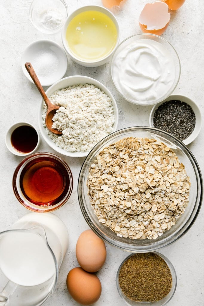 All ingredients for baked vanilla protein oatmeal bars arranged in small bowls. 