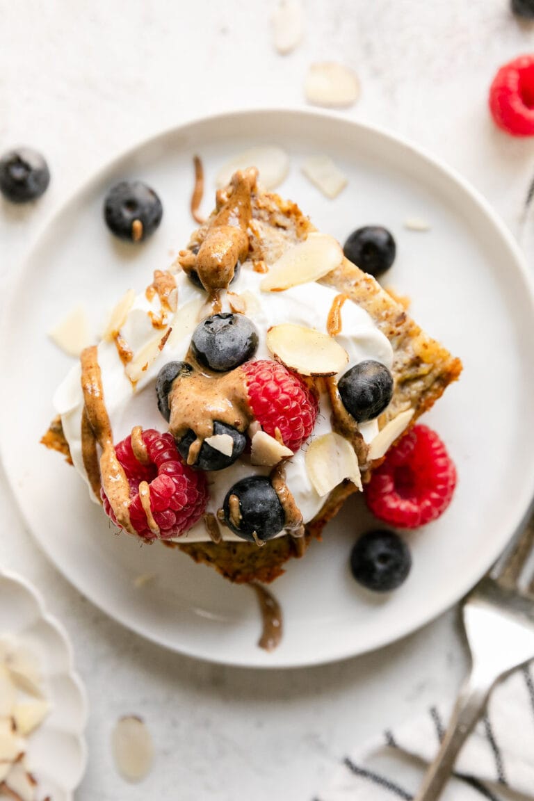 Overhead view of a piece of baked vanilla protein oatmeal topped with yogurt and fresh berries and drizzled with nut butter. 