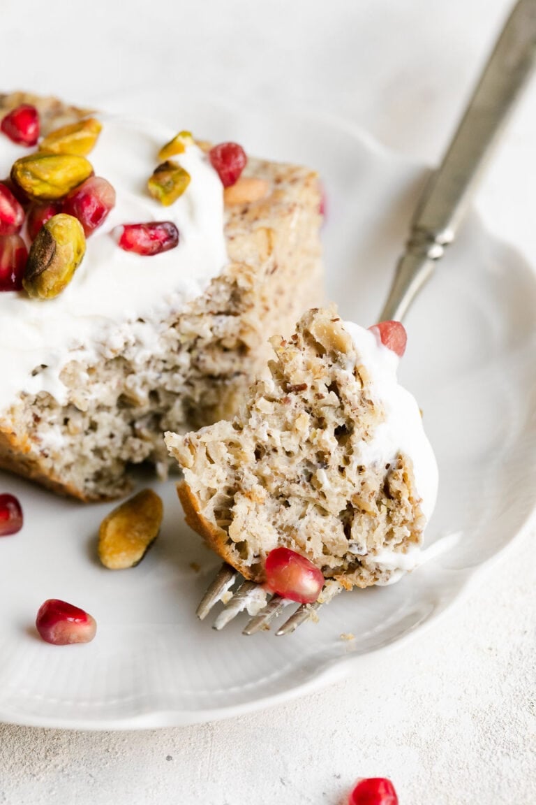 Forkful of baked vanilla protein oatmeal next to serving of protein baked oatmeal on white plate