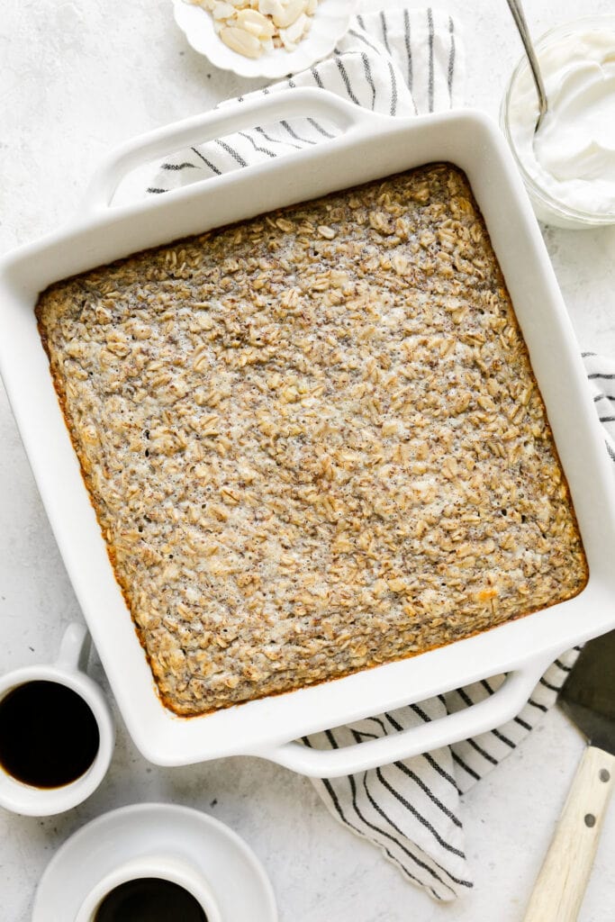 Baked oatmeal in a white baking dish with blue and white striped dish cloth underneath.