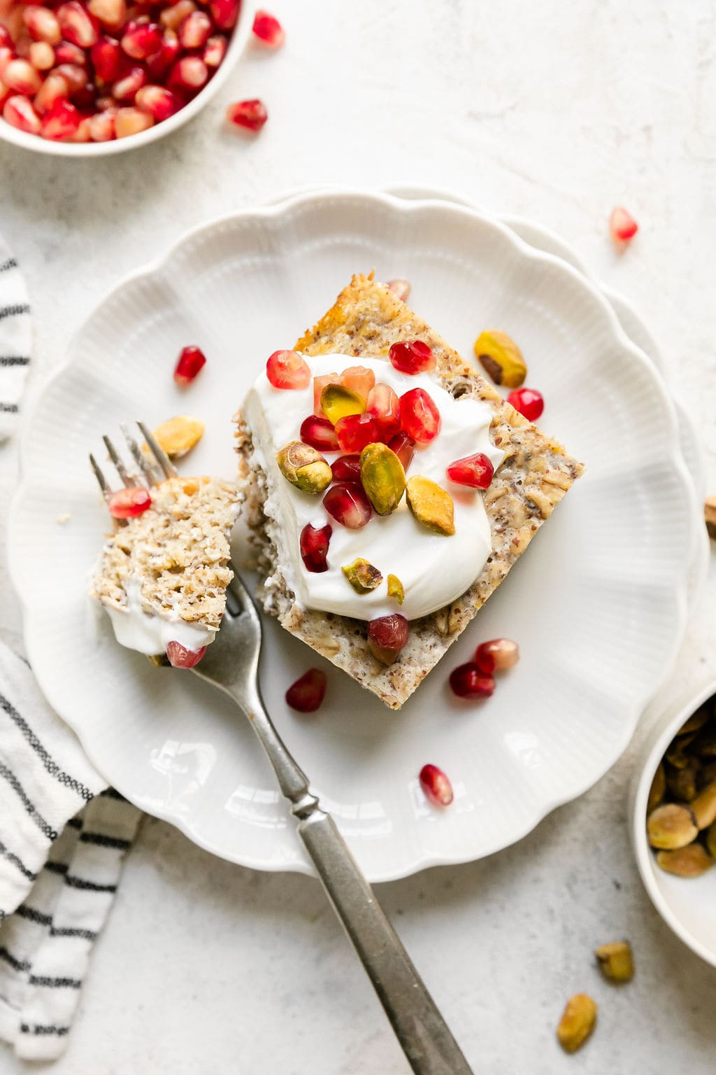 Overhead view serving of protein baked oatmeal on white plate, topped with Greek yogurt and fresh berries.