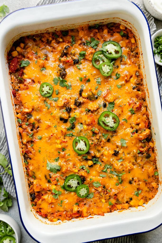 Overhead view baking dish with Southwest chicken quinoa casserole, topped with melted cheddar cheese.