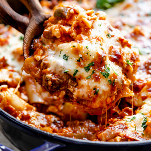 A wooden spoon scooping out serving of easy skillet lasagna with melty mozzarella cheese topping.