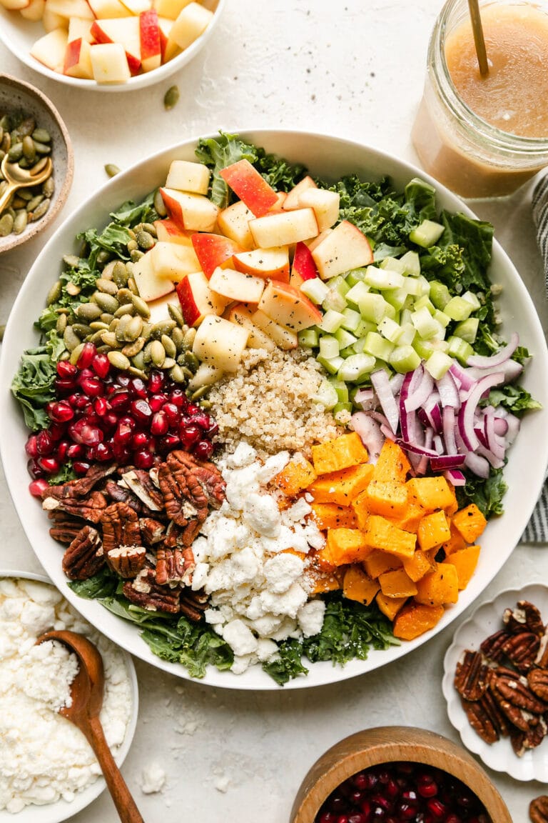 Overhead view of a bowl filled with a variety of colorful salad ingredients including apples and cubed squash.