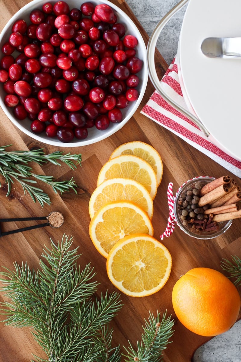 Overhead view all ingredients for Holiday Simmer Potpourri arranged on wooden cutting board. 