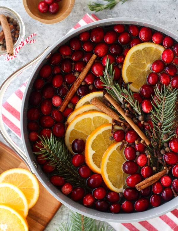 Overhead view white pot filled with ingredients for Christmas Simmer Pot, sitting on red and white striped towel.