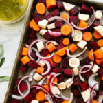 Chopped carrots, parsnips, sweet potatoes, and beets on a baking sheet ready to be coated in glaze.