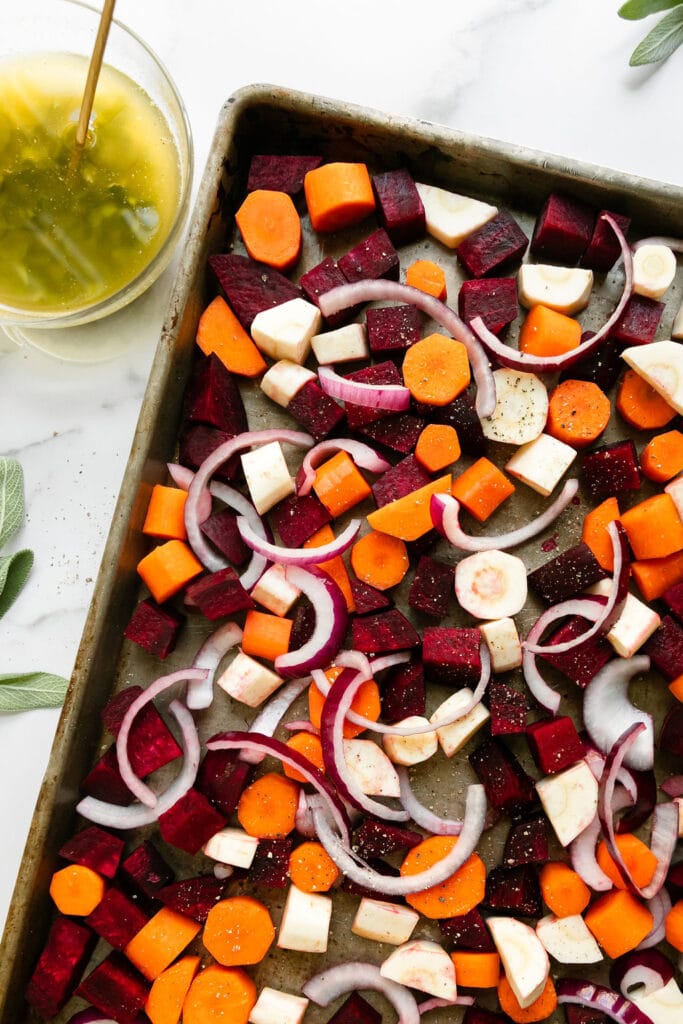 Chopped beets, parsnips, sweet potatoes, and carrots on a baking sheet.