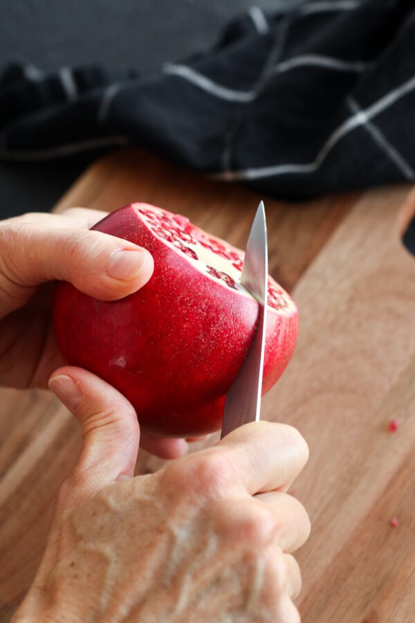 A pomegranate being cut dow the side.