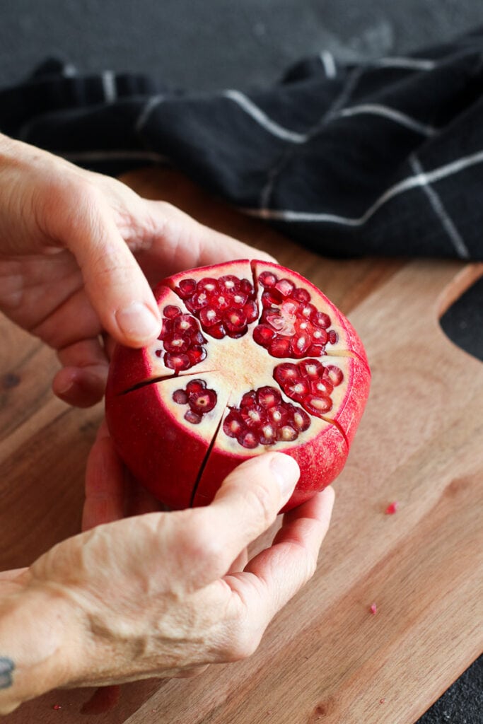 A pomegranate cut along sections, arils showing on the end.